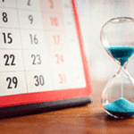 Hourglass with blue sand next to a calendar