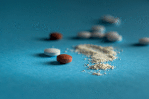 Pills next to brownish powder on a blue background