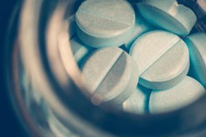 Blue opioid pills in a jar