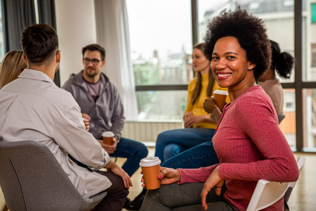 Diverse group of people sitting in circle in group therapy session.