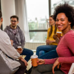 Diverse group of people sitting in circle in group therapy session.