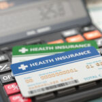 Medical insurance cards on the calculator. Health care costs concept. 3d illustration