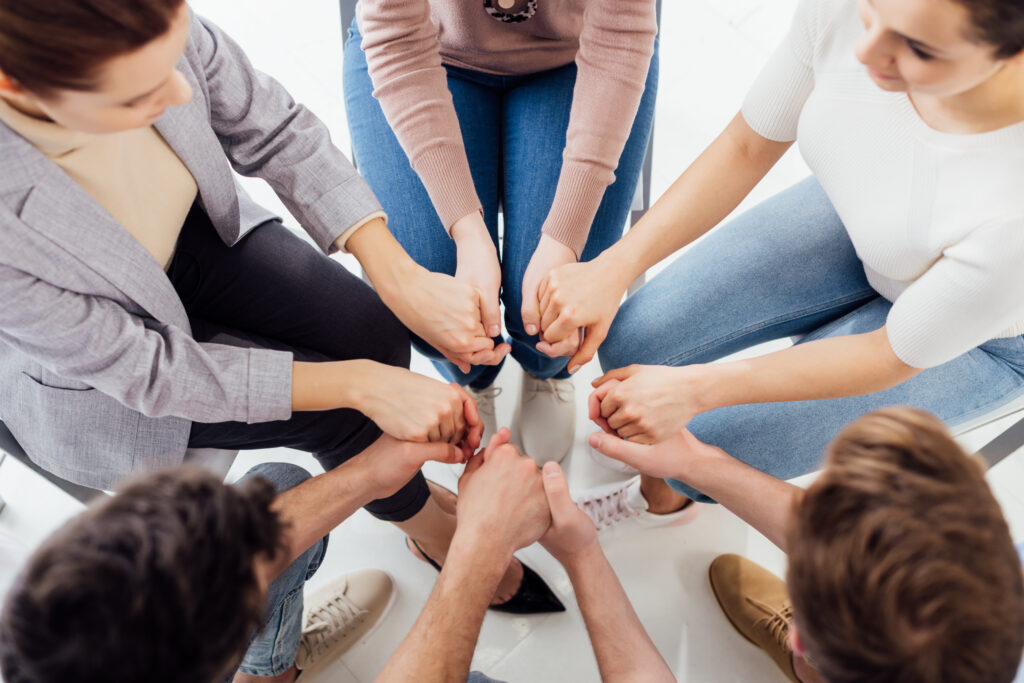 top view of people holding hands during group therapy session