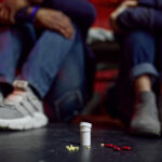 Drug addicts sitting on the floor in den, grunge place interoir on background, pill-addicted. Narcotic addiction problem, eternal depression of junky people