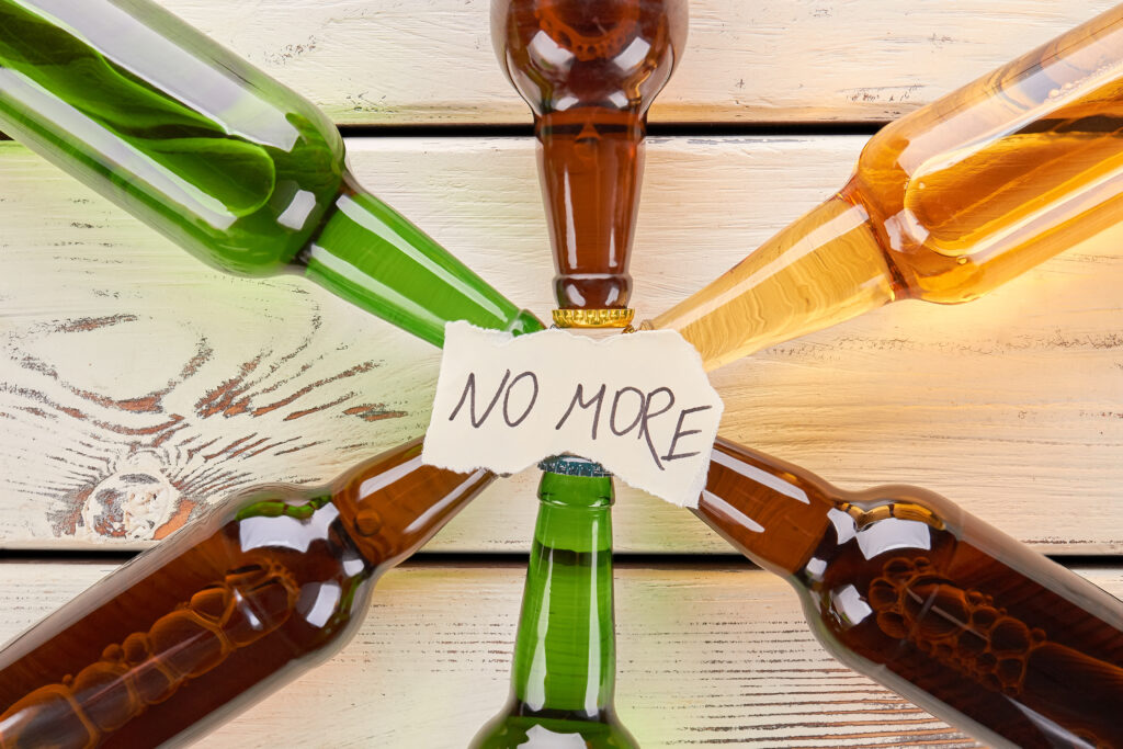 No more to alcohol drinking, concept. Paper message on collection of glass bottles.