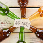 No more to alcohol drinking, concept. Paper message on collection of glass bottles.