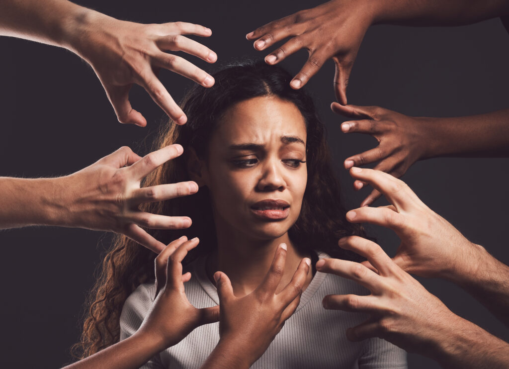 Shot of hands grabbing a young womans against a dark background.