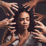 Shot of hands grabbing a young womans against a dark background.