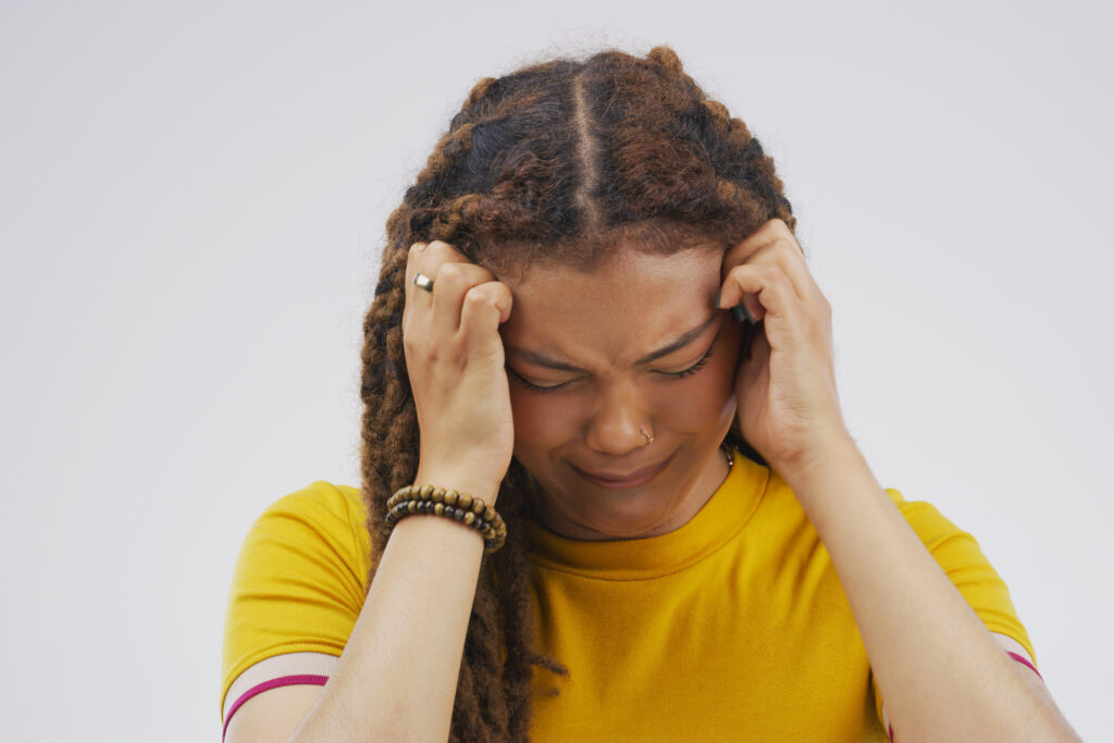 Studio shot of a young woman crying while standing against a gray background.