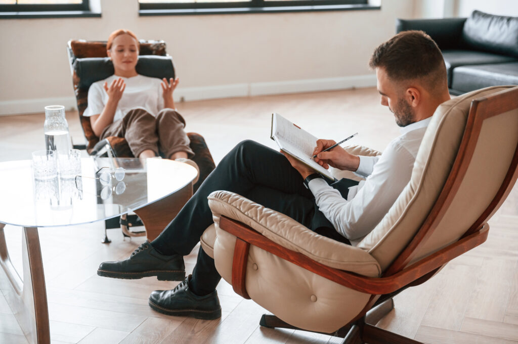 Woman is sitting in chair at an appointment with a psychologist.