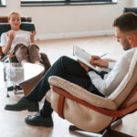 Woman is sitting in chair at an appointment with a psychologist.