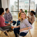 Diverse group of people sitting in circle in group therapy session.
