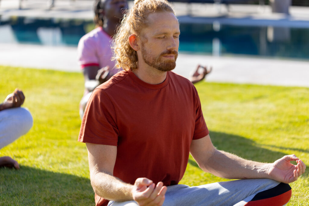 Group of diverse friends doing yoga and meditating in garden. Friendship, healthy and active lifestyle, summer, sunshine, unaltered.