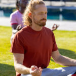 Group of diverse friends doing yoga and meditating in garden. Friendship, healthy and active lifestyle, summer, sunshine, unaltered.