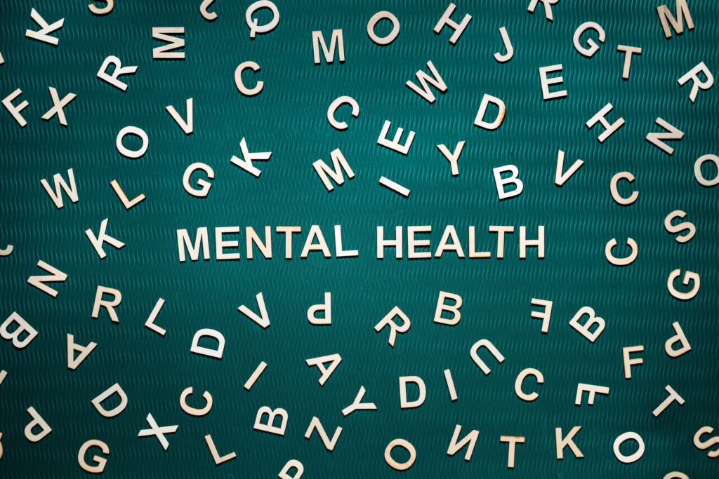 Mental health word from wooden letters. Mental health text on green background with many other letters
