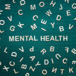 Mental health word from wooden letters. Mental health text on green background with many other letters