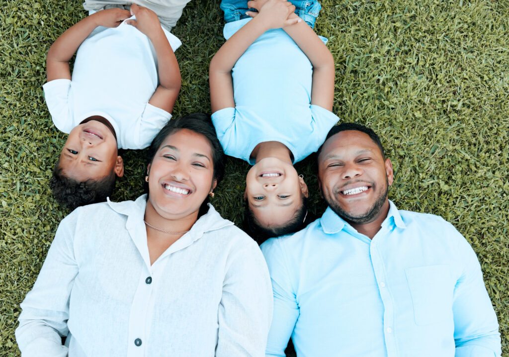 Shot of a couple and their two two children lying outside on the grass.