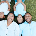 Shot of a couple and their two two children lying outside on the grass.