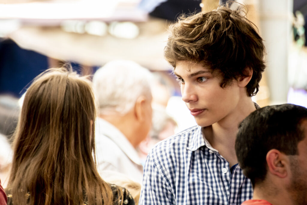young male walking in a crowd in a city street during daytime in a sunny season