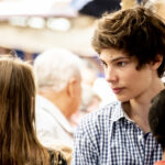 young male walking in a crowd in a city street during daytime in a sunny season