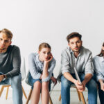 Group of young candidates with resume and gadgets looking at camera in office