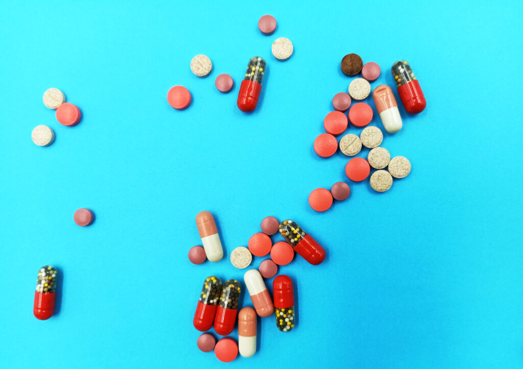 A top view of medical pills and capsules isolated on a blue background, Medical concept of treatment diseases